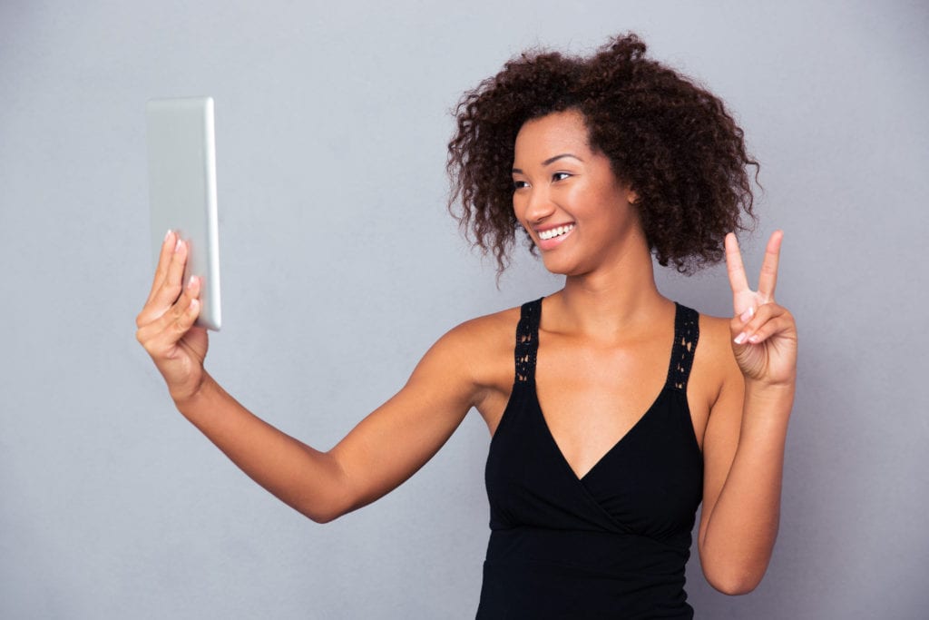 Smiling woman holding a tablet while video chatting on the go.