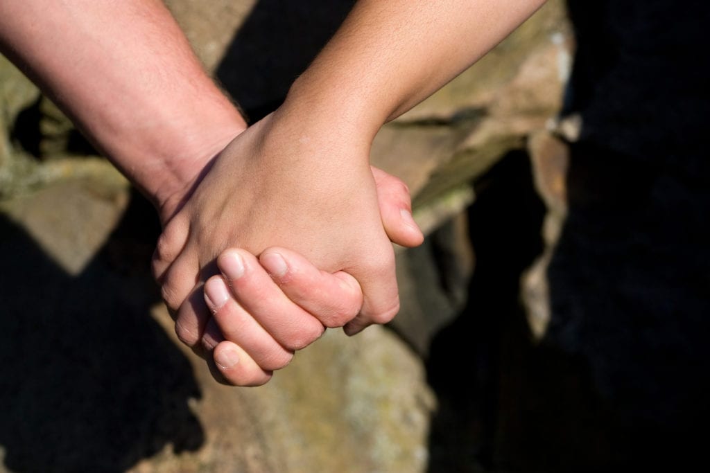 Couple holding hands, symbolizing connection and affection in relationships.