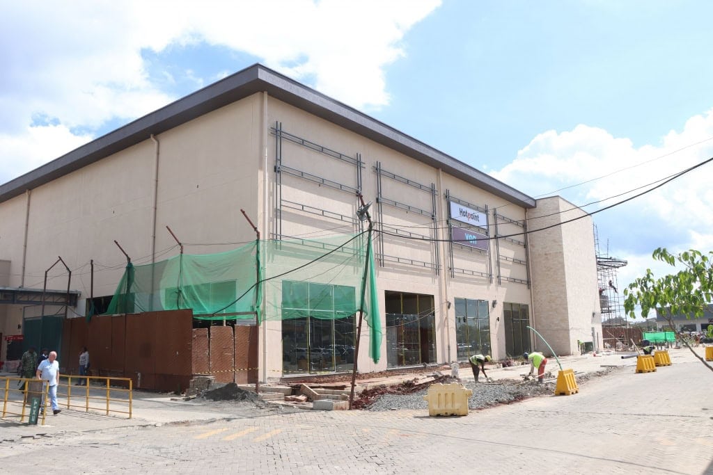 A beige building facade remains under construction with scaffolding and safety barriers