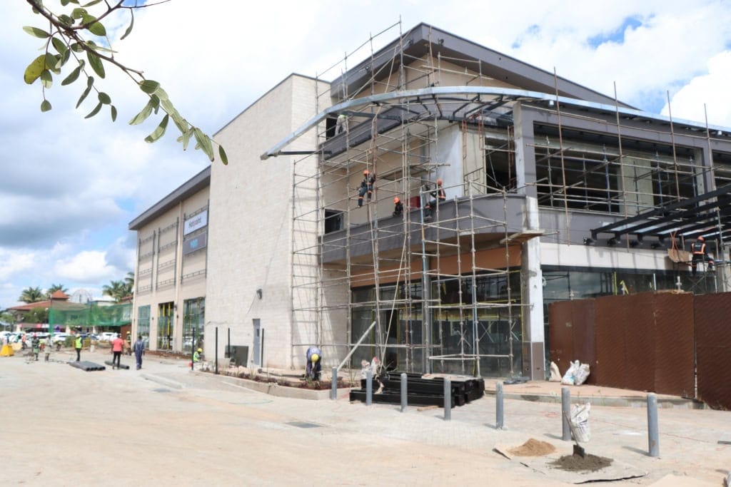 Workers stand on scaffolding beside a mall building under construction.