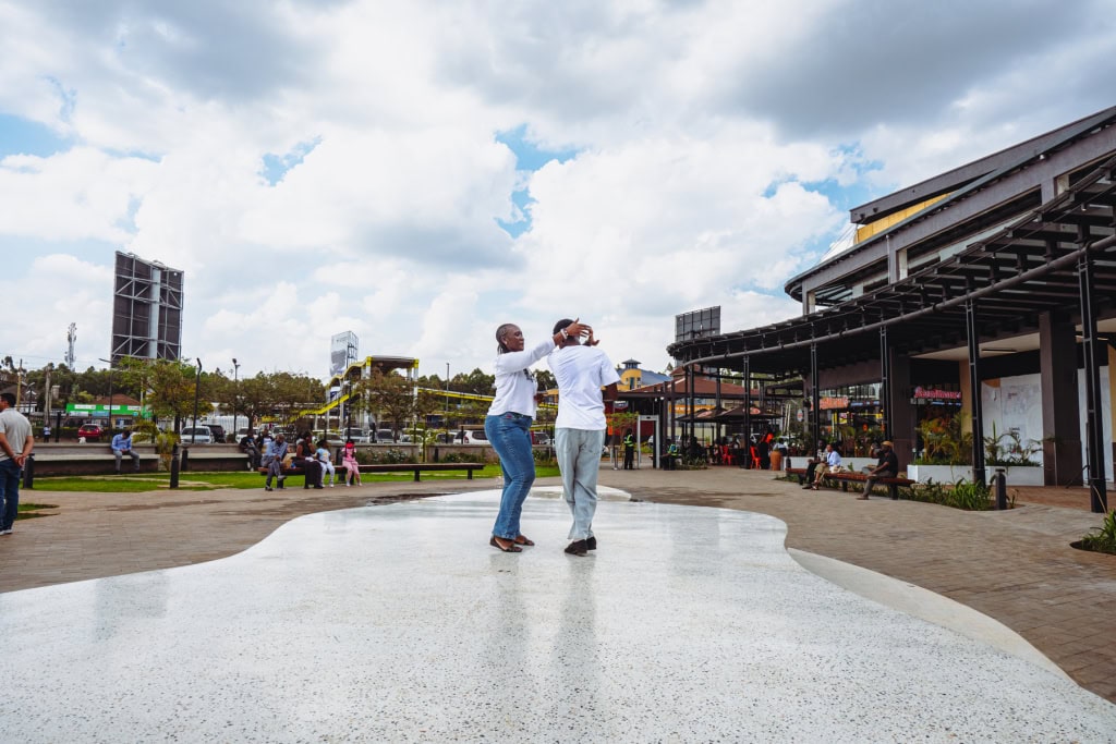 Two dancers perform in the center of a wide outdoor mall plaza