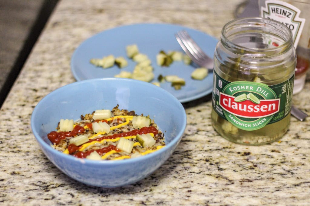Adding claussen pickles to the burger in a bowl recipe.