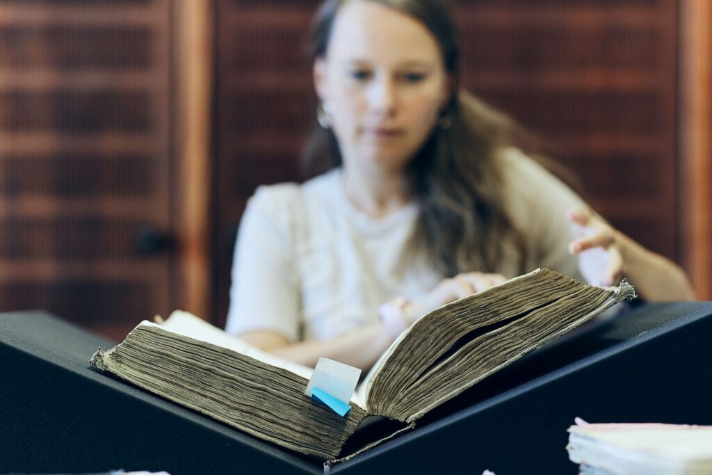 Eine Archivnutzerin blättert in einem Buch.