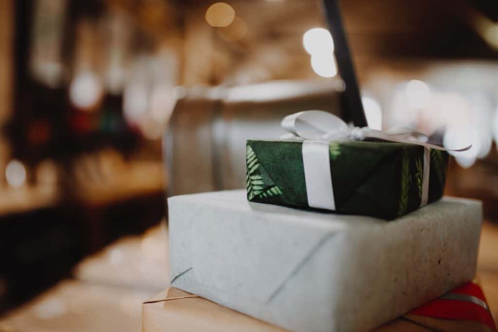 three gifts stacked on top of each other wrapped in Christmas themed wrapping paper