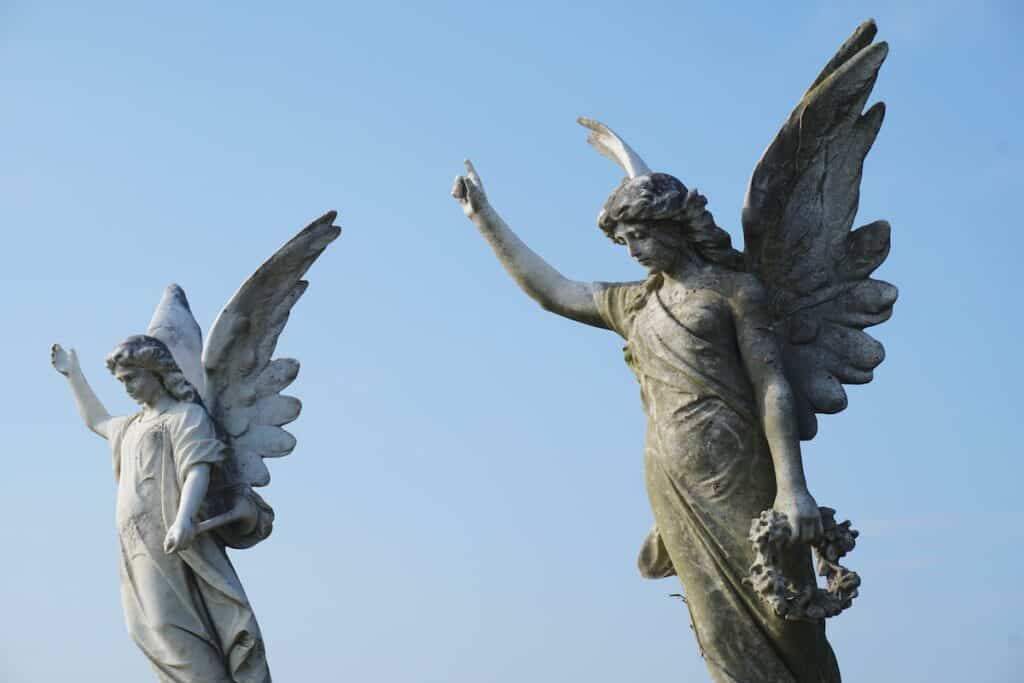 two statues of angels against blue sky