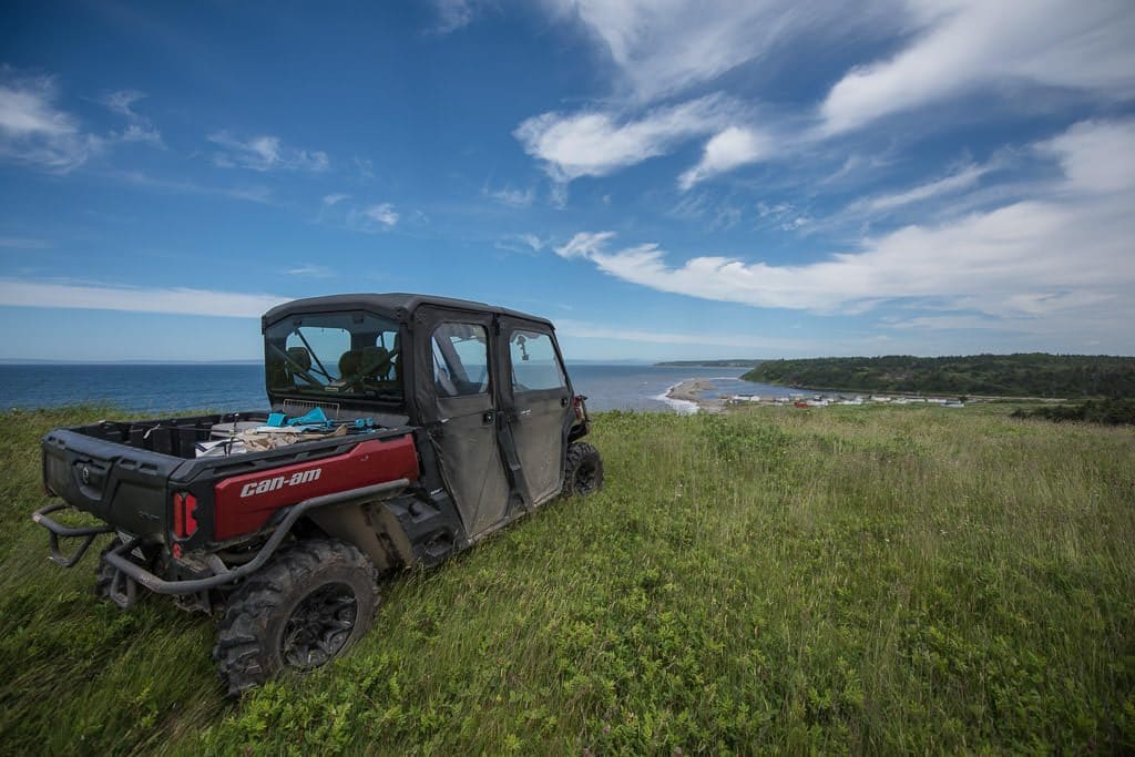 Newfoundland ATV sitting in high grass on the top of a hill overlooking the coast.