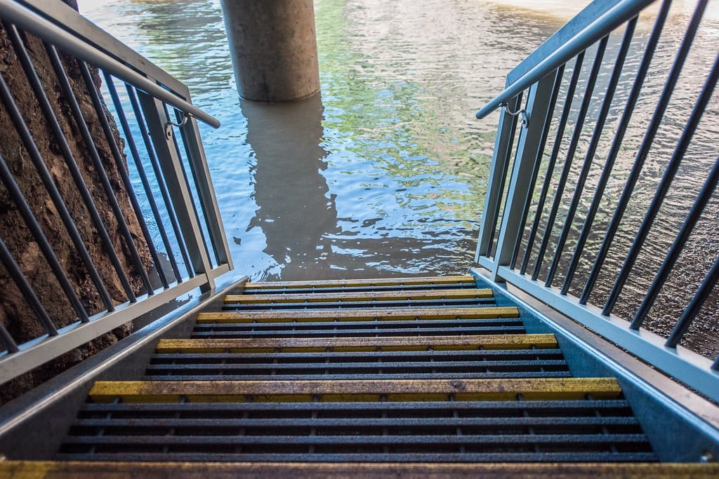 water coming over the stairs leading down to the beach during low tide.