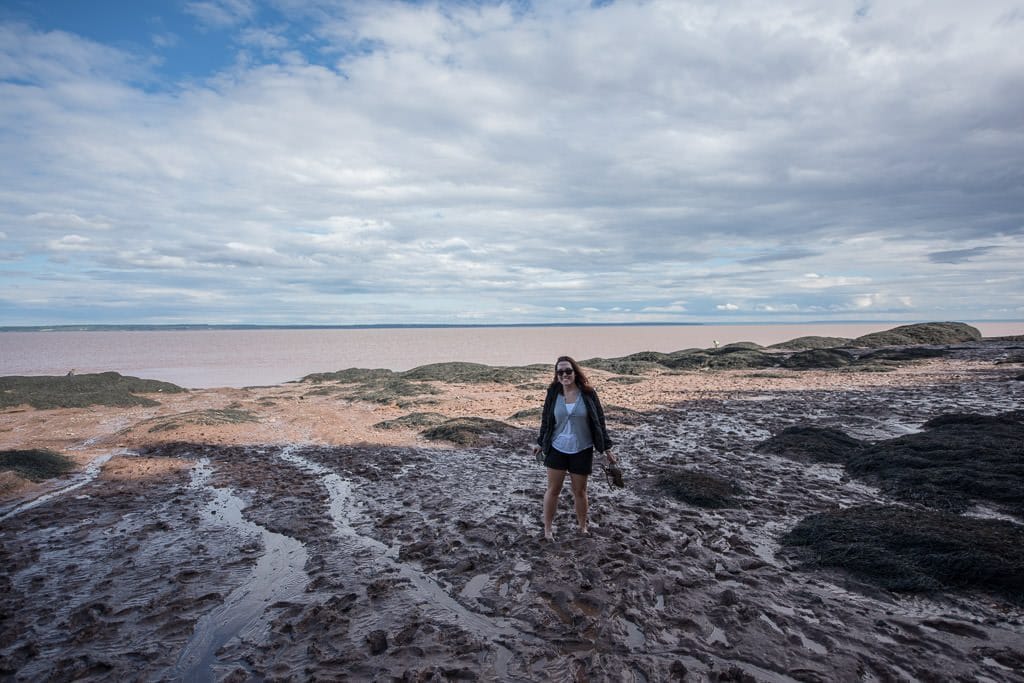 Brooke walking on the muddy ocean floor at hopewell rocks in the Bay of Fundy