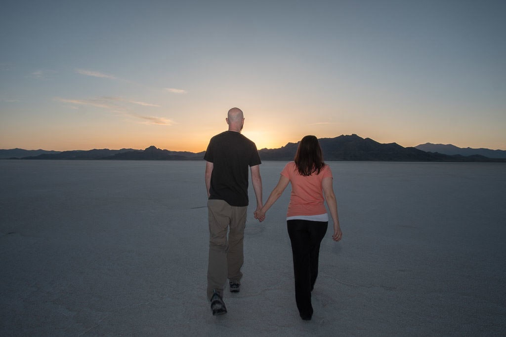 Brooke and Buddy hand-in-hand walking on the Bonneville Salt Flats during sunset