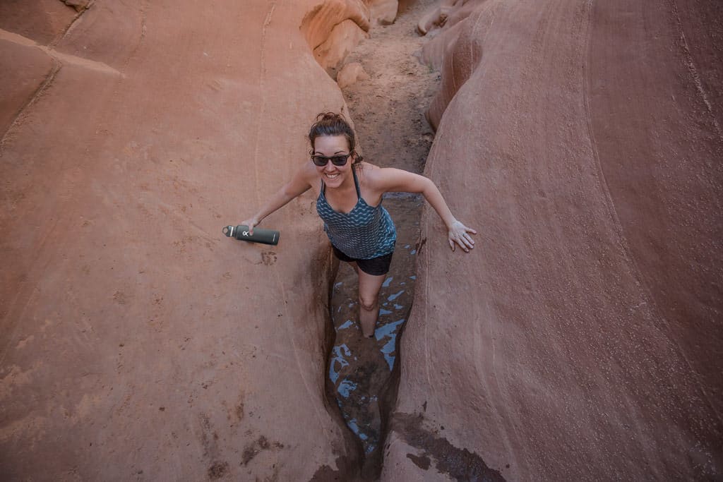 Brooke in knee high water hiking through a narrow section of Antelope Canyon on Lake Powell