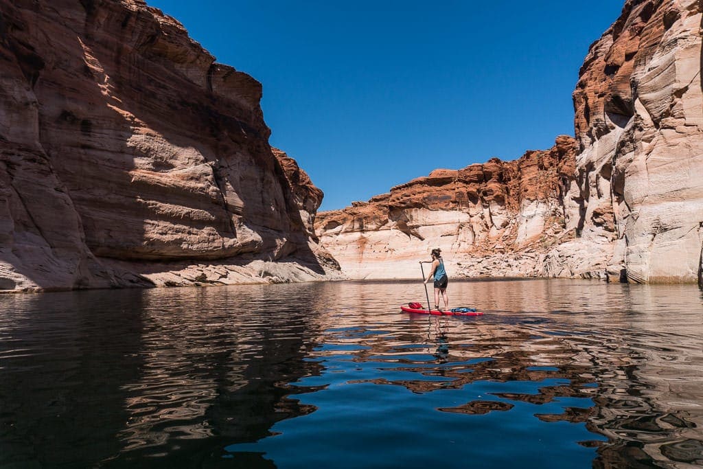 Brooke Paddleboarding on Lake Powell between giant rock cliffs on the way to Antelope Canyon in Page Arizona