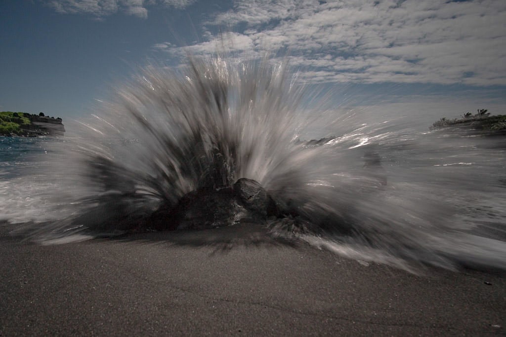 wave crashing against a rock on the black sand beach in Wai'anapanapa State Park