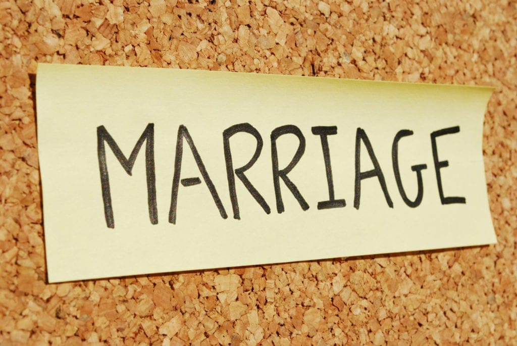 Sticky note with the word “Marriage” pinned to a cork board, symbolizing wedding or commitment concepts