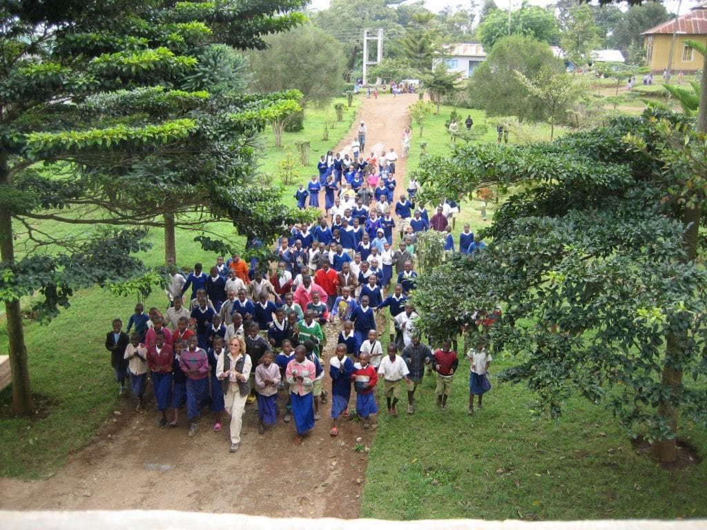 Shot from overhead of author leading over 60 African children into a church for Bible study time.