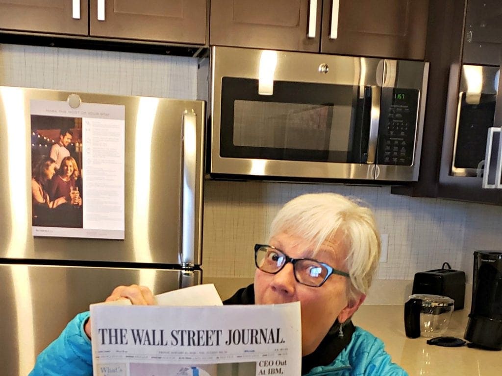 Arizona travel writer Stacey Wittig reads complimentary Wall St Journal in her suite with stainless steel refrigerator, microwave and coffee maker behind her at The Residence Inn Flagstaff