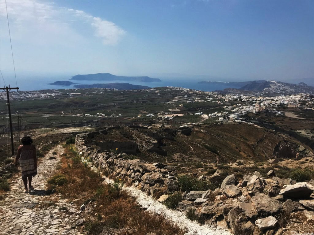 girl walking on the downhill road Elias monastery seeing santorini from above