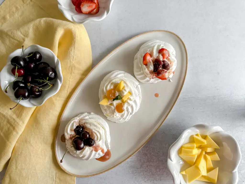 Mini Pavlova on a oval plate with bowls of fruits