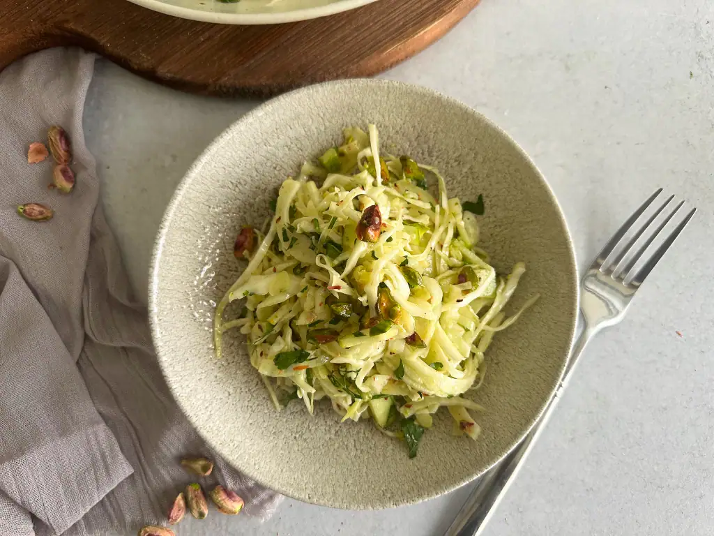 Cabbage recipe with apples, fennel and pistacchios in a bowl.