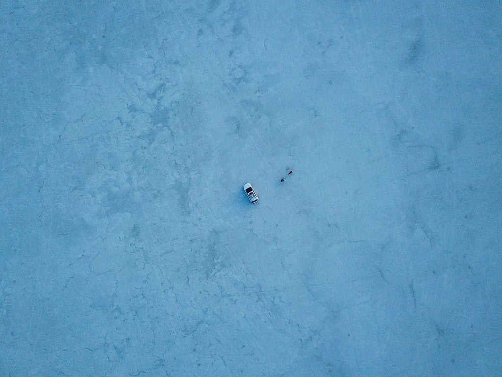 Aerial photo of Brooke and Buddy standing outside of the car on the Bonneville Salt Flats