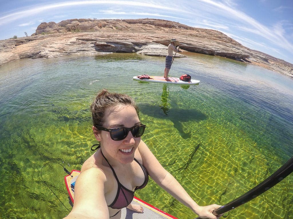 Brooke taking a selfie on her Paddleboard while Buddy is paddling his over the very clear water of Lake Powell