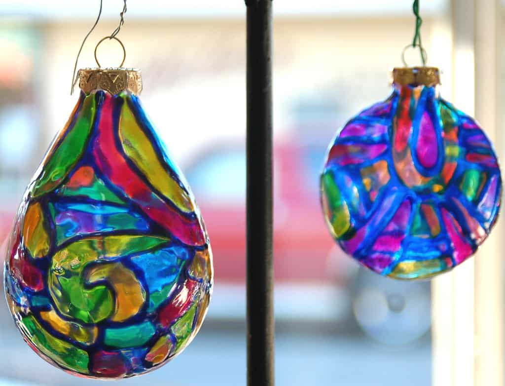 Two painted glass ornaments in a window with bright colors