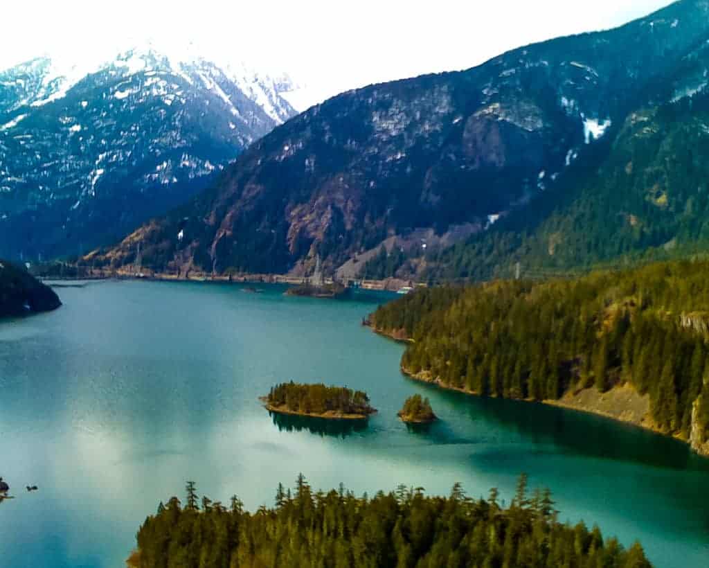 View of snow covered mountains with Diablo Lake's beautiful green water and evergreen-treed islands, Cascade Mountains, Washington State