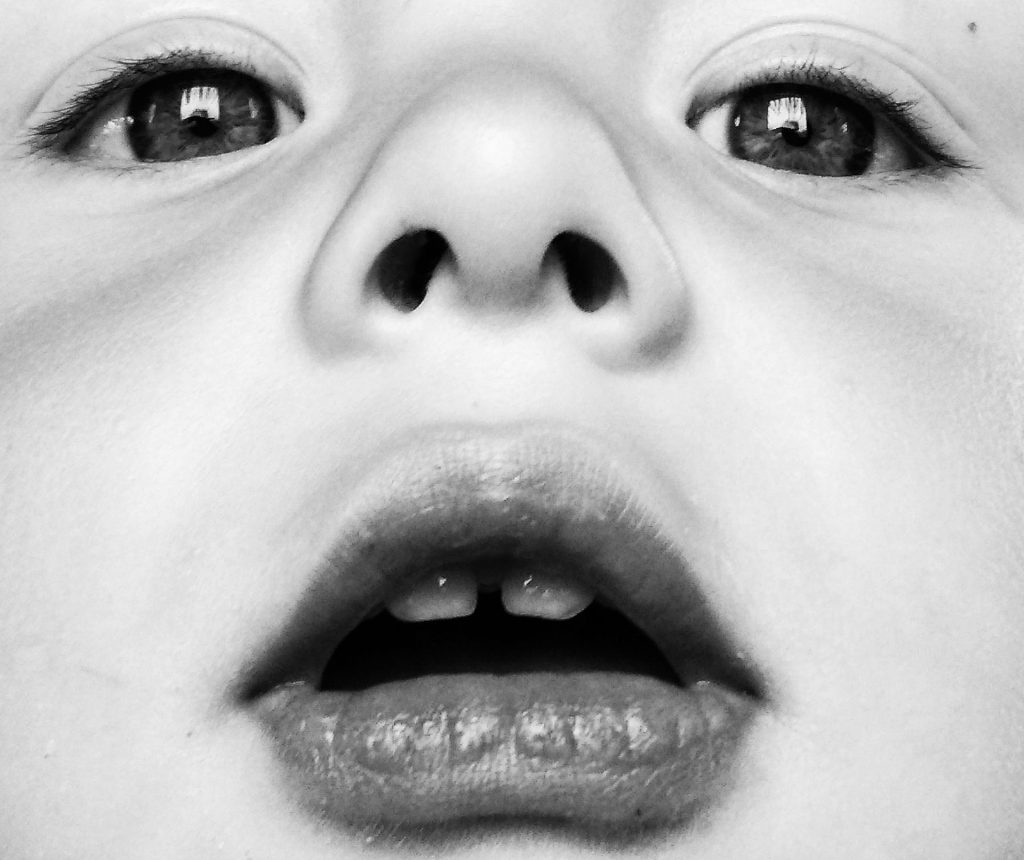 Close up of a blank stare on a young child's face in black and white, as if to represent disconnection, or isolation