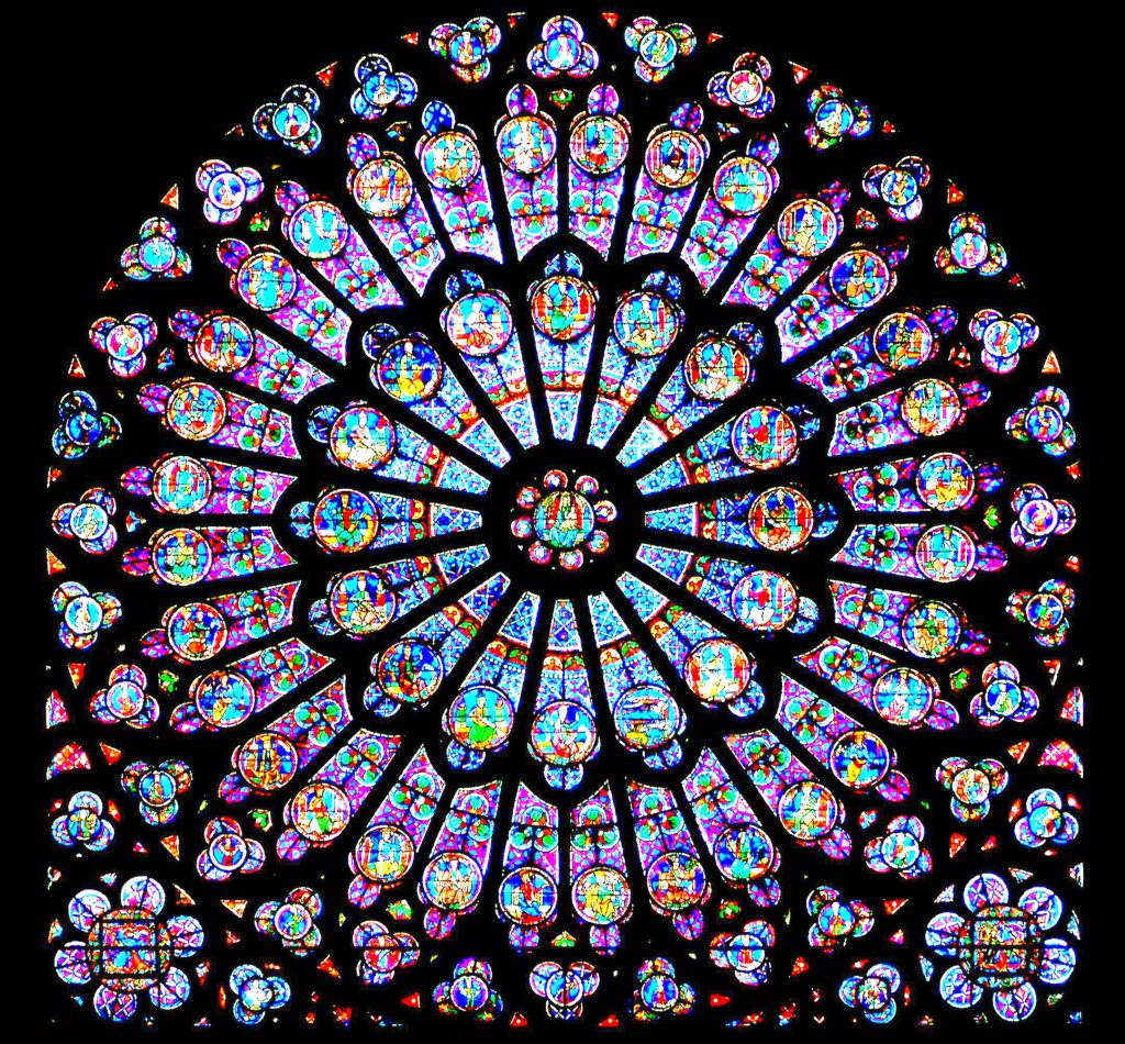 Huge round window full of blue and purple glass depicting Bible stories that cannot be discerned from this distance is silhouetted against the dark, black walls of the cathedral's interior walls makes this a great piece for experiencing God in art