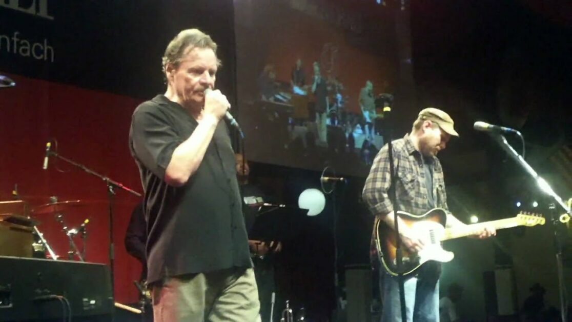 Dilbert McClinton on stage singing in microphone