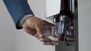 Office worker pouring a glass of water from a commercial water cooler