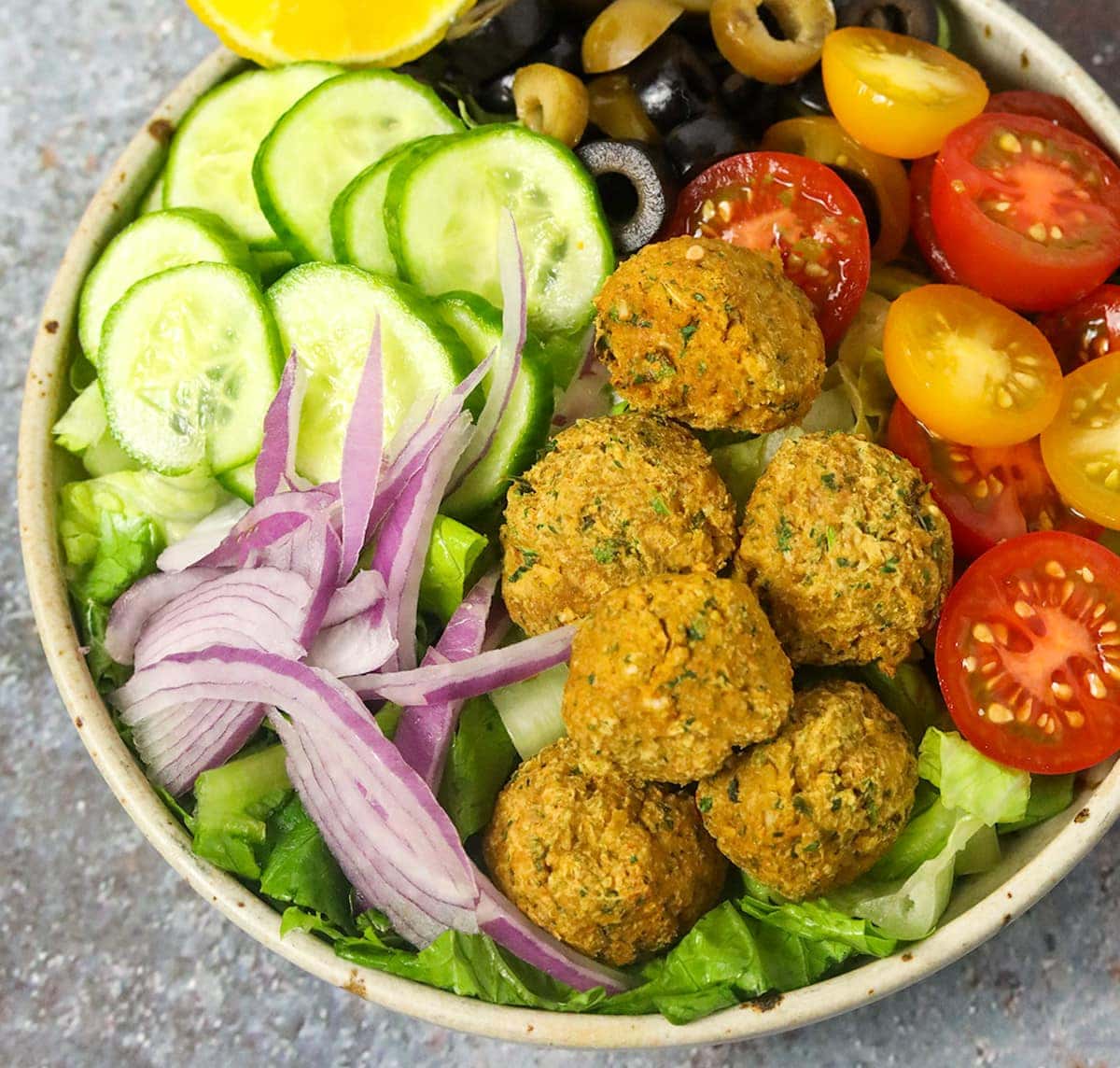 Close view of falafel salad in a bowl on a grey background