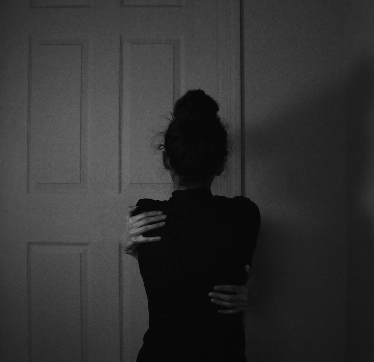 black and white image of the back of a woman giving herself a compassionate self hug