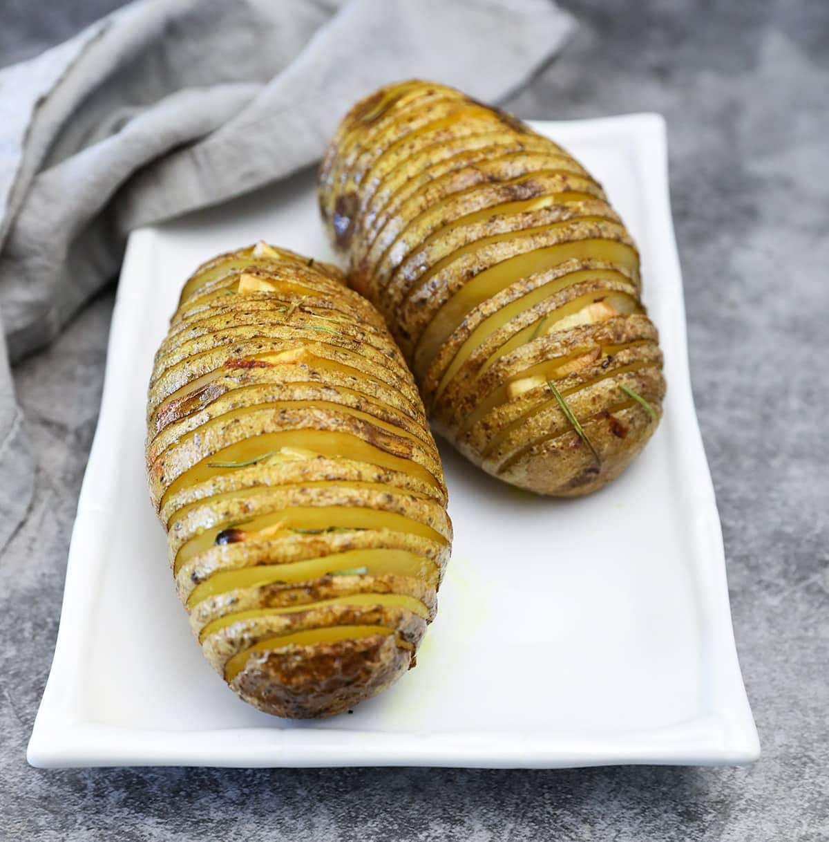 hasselback potatoes close up on a white plate on a grey background