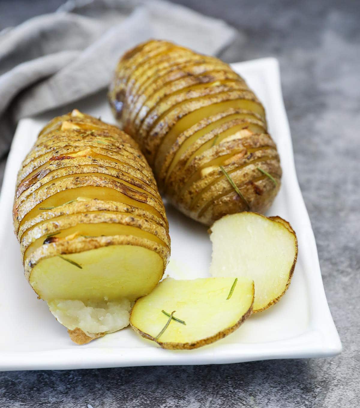 hasselback potatoes, cooked , served on white plate