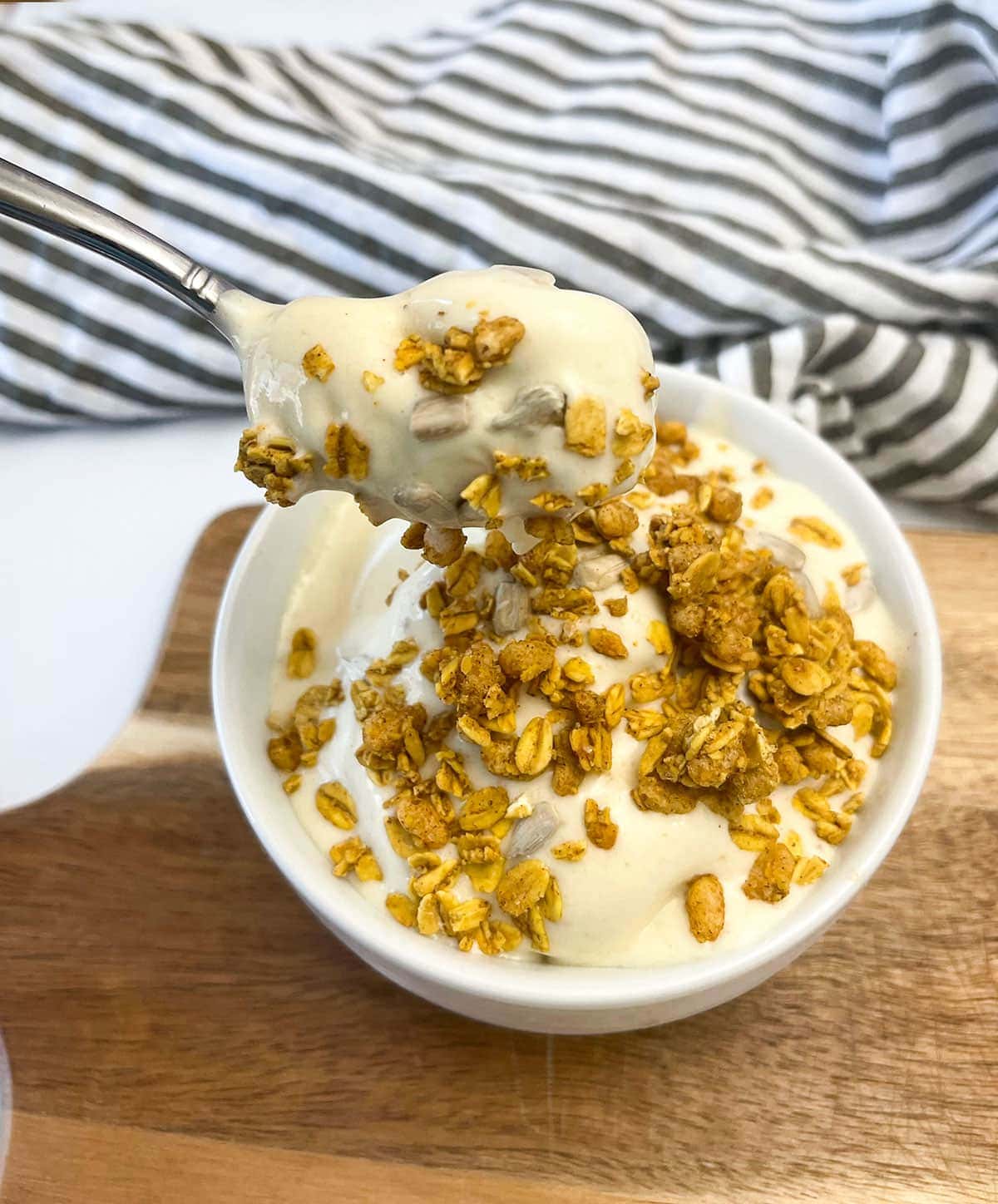 banana ice cream with granola in a white bowl on a wooden background
