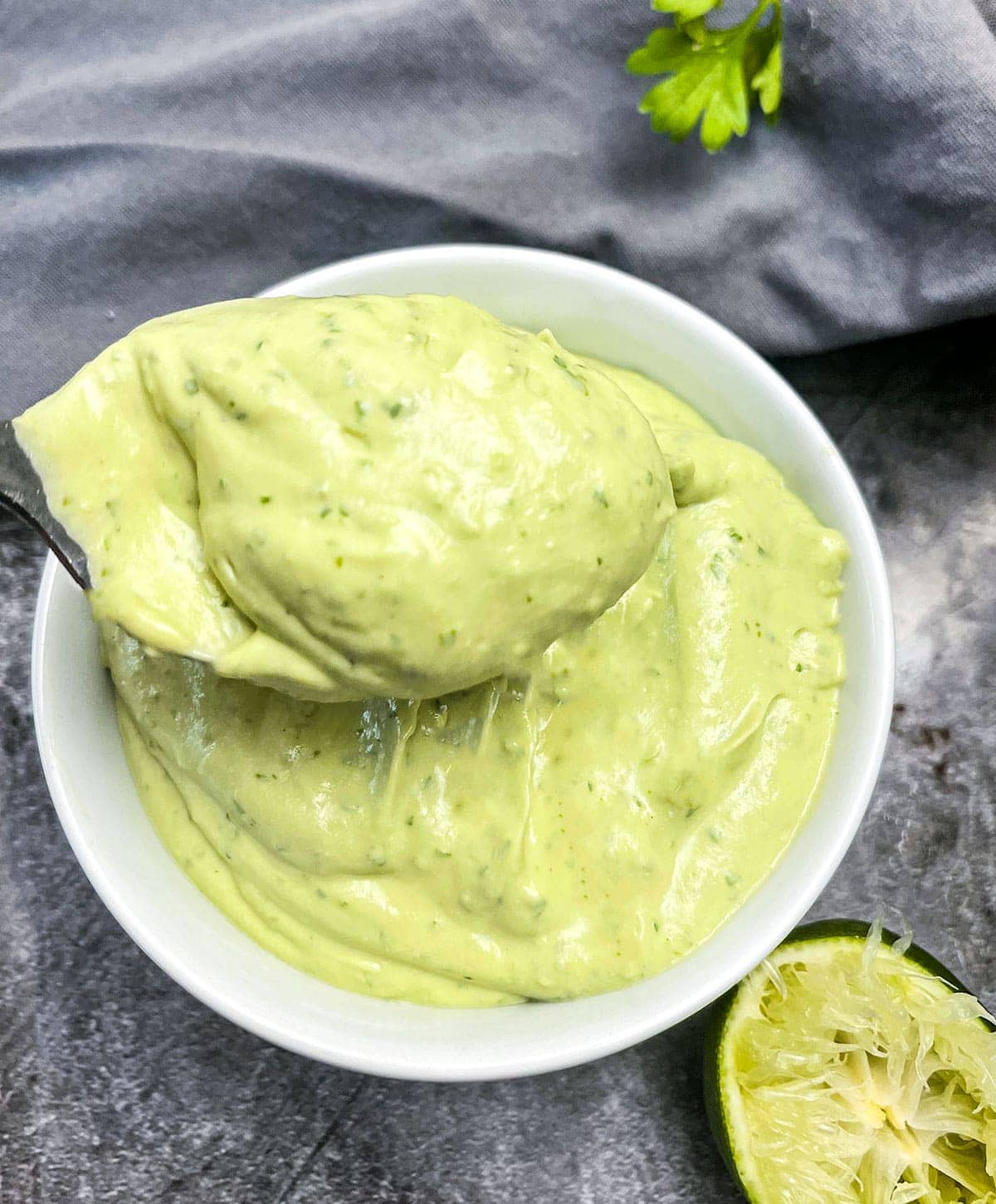 avocado lime crema a spoonful taken from a white bowl