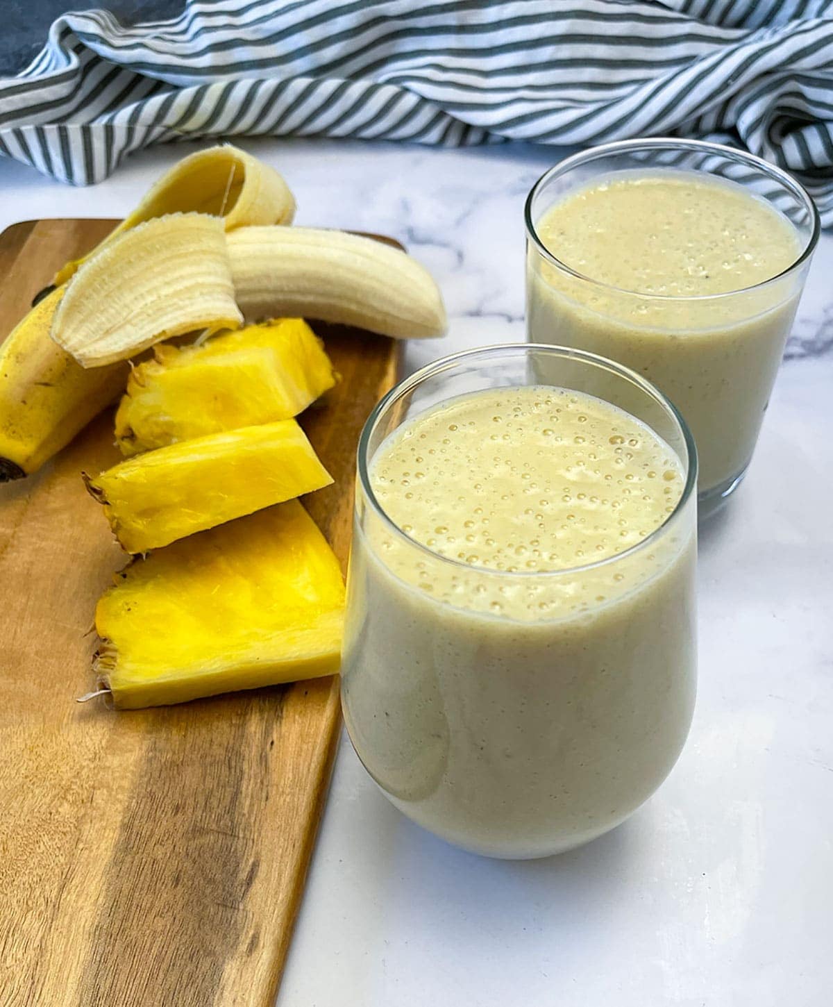 overlay pineapple banana smoothie in 2 glasses