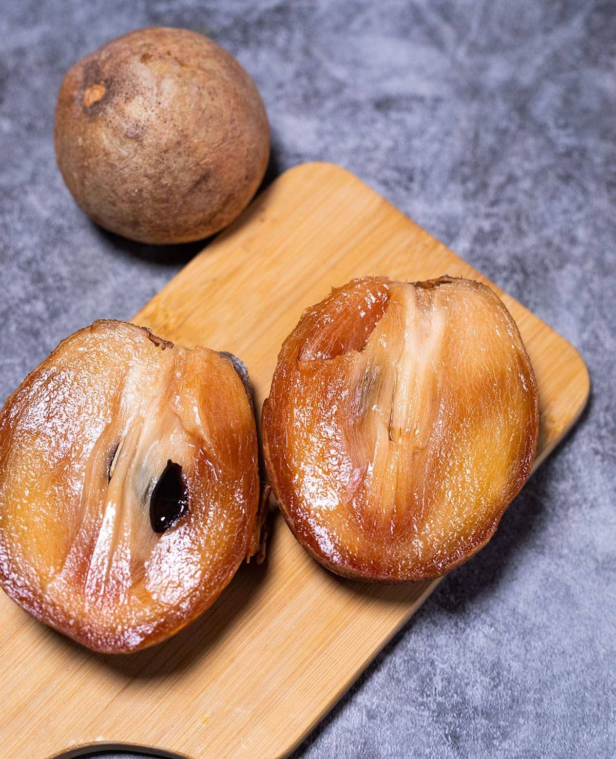 naseberry sapodilla cut in half on cutting board