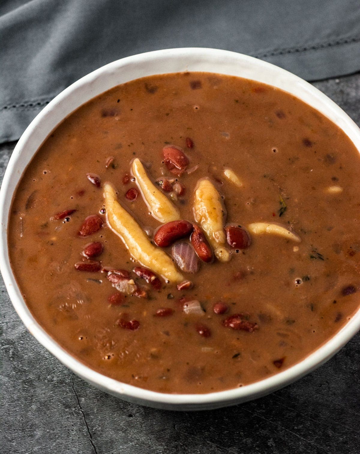 Overlay Red peas soup with dumplings in a white bowl on a grey background