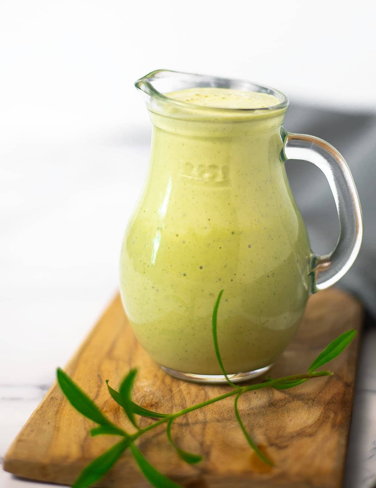 tarragon salad dressing in a glass container on a cutting board