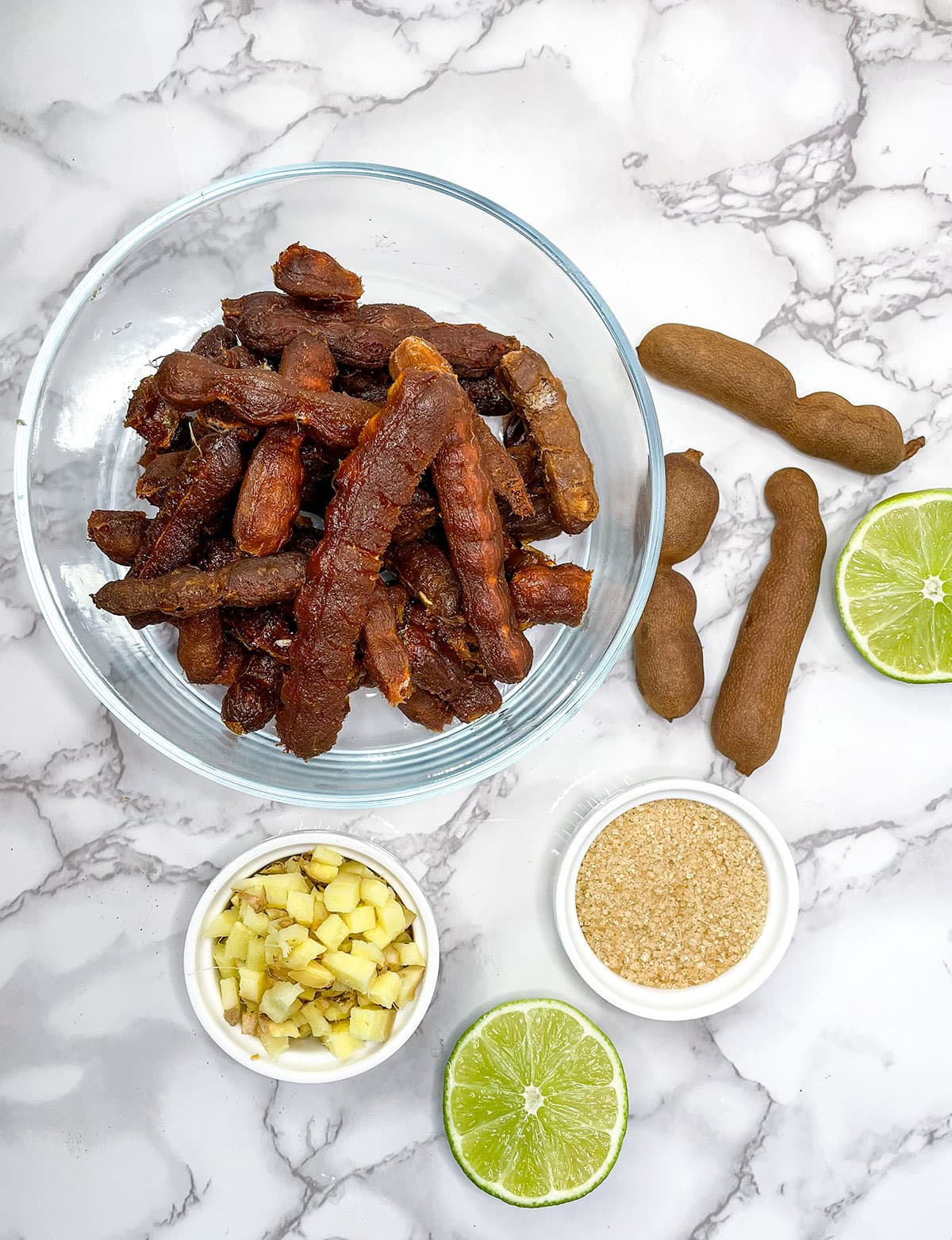 ingredients prepped, tamarinds deshelled in a glass bowl on a white background