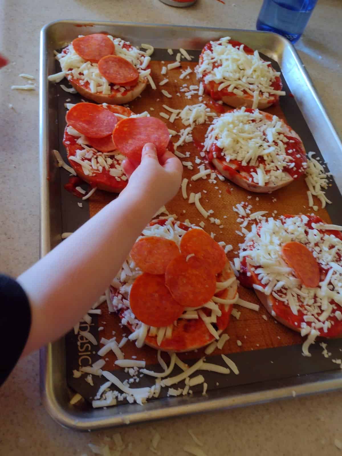 Picture of toddler putting pepperoni on a bagel