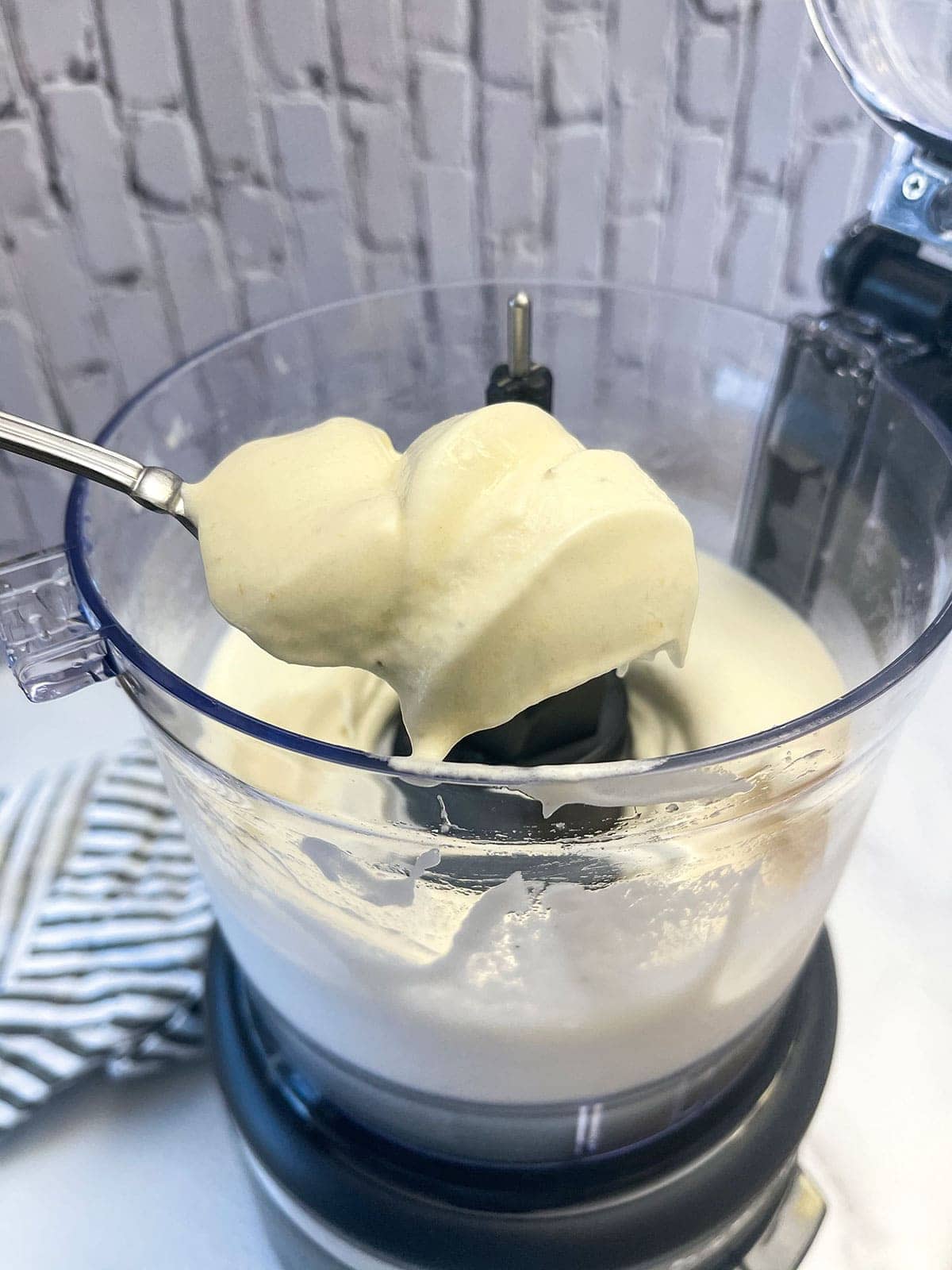 creamy banana ice cream in food processor on a white background