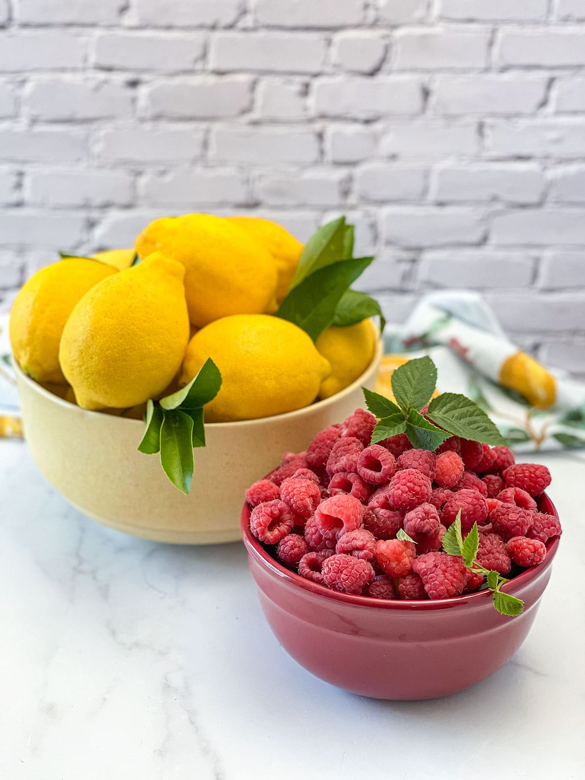raspberries and lemons in bowls on a white background