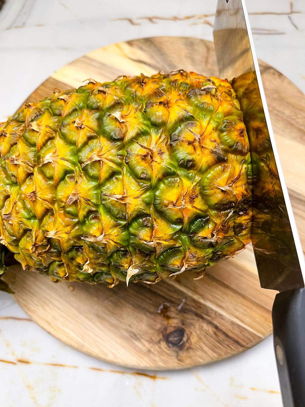how to peel a pineapple, cutting the base off the pineapple with a knife