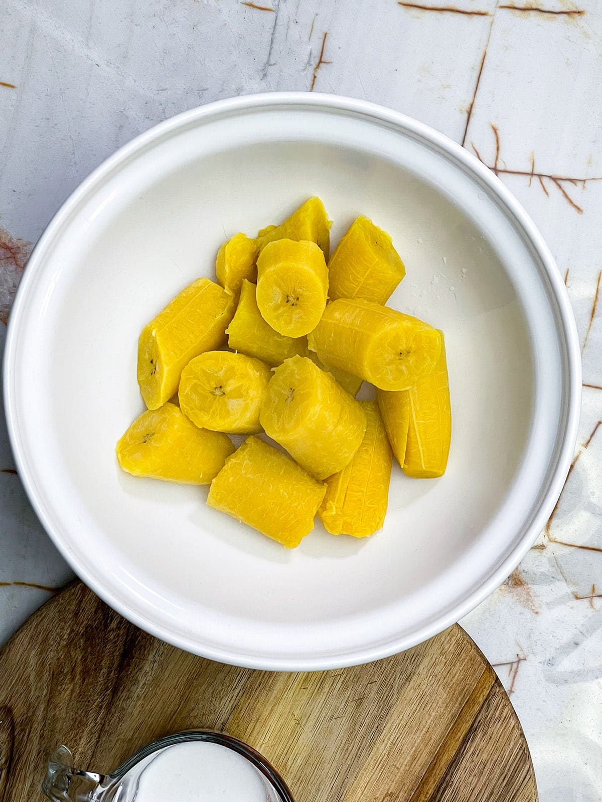 boiled plantains in a white bowl on a beige background