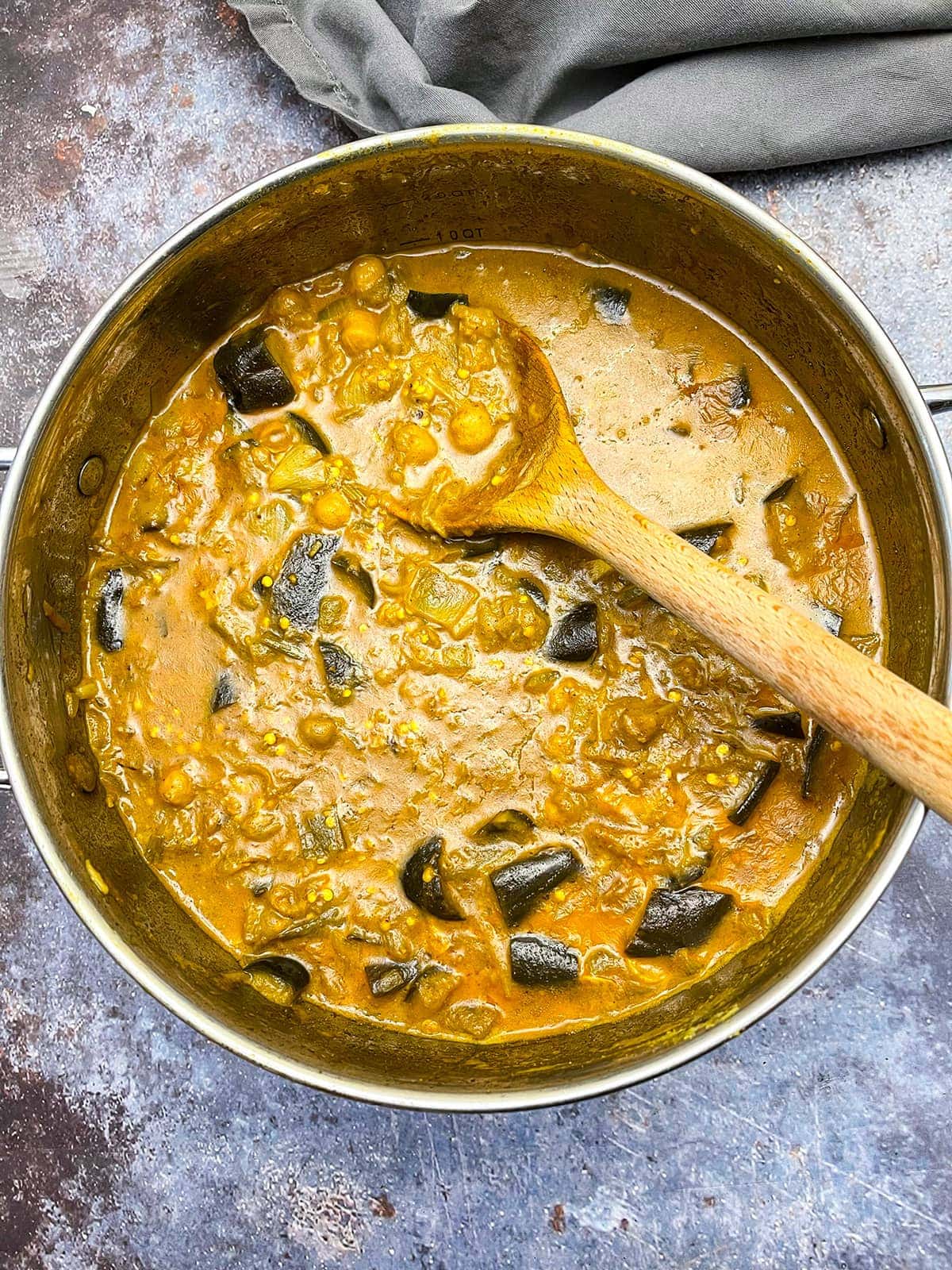 eggplant chickpea curry overlay in a saucepan on a grey background