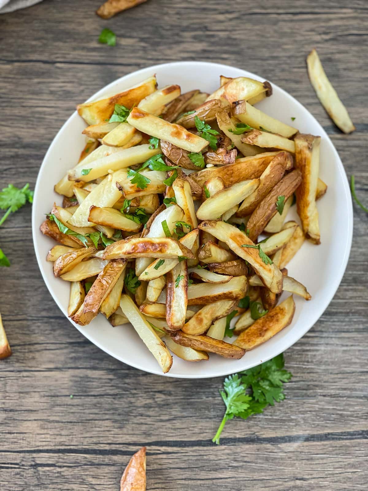 cilantro fries recipe in a white bowl on a wooden background