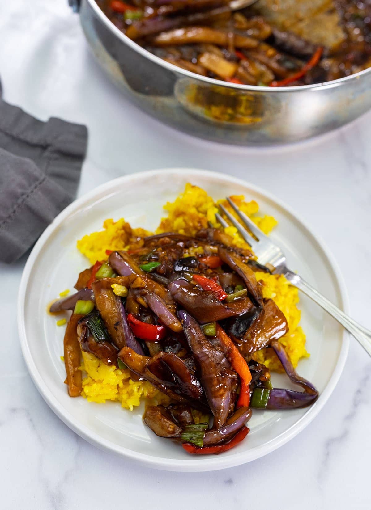 eggplant in garlic sauce over rice on a white plate