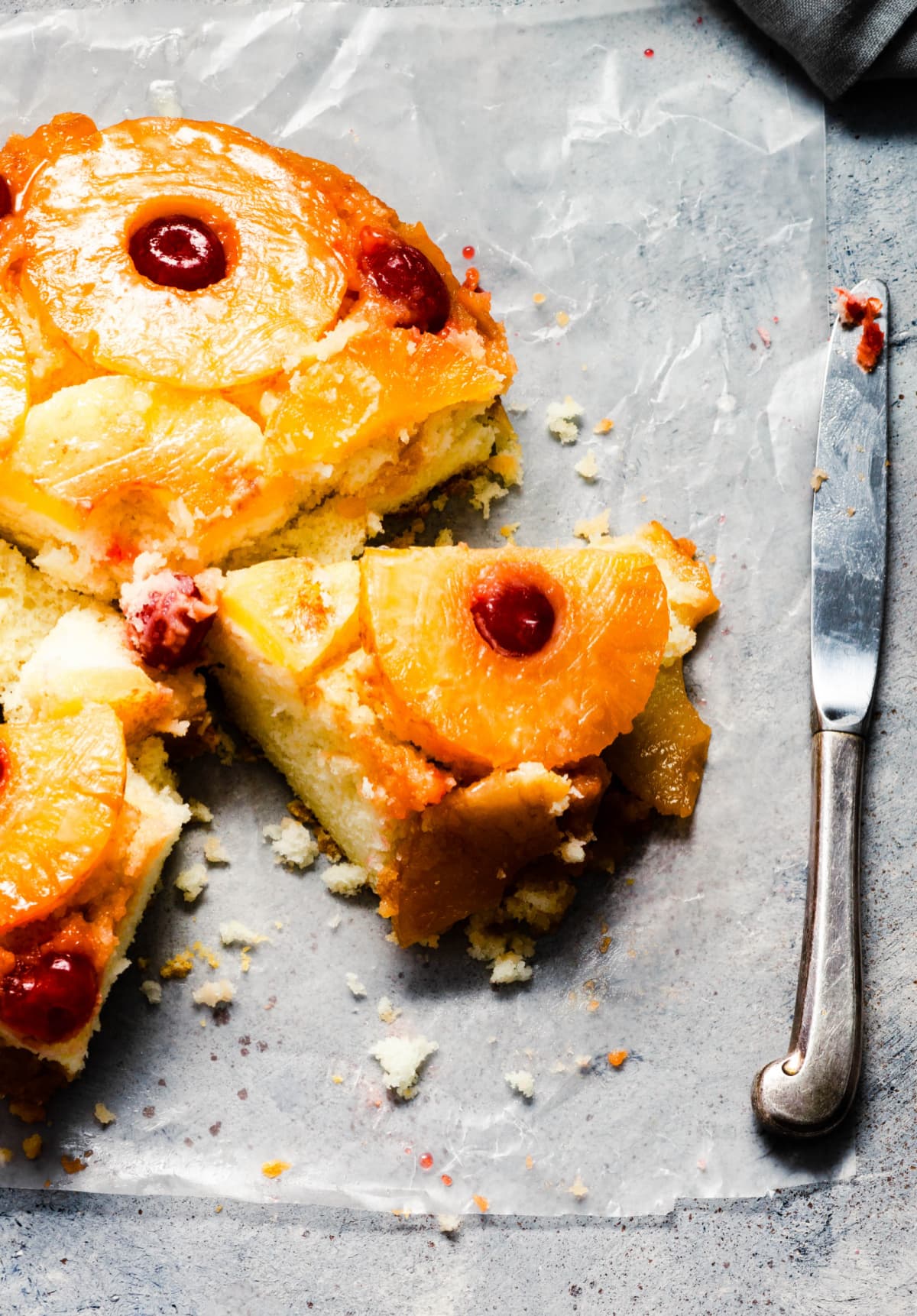 pineapple upside down cake with one slice removed on parchment paper